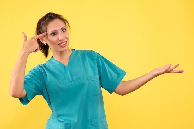 Vue de face femme médecin en chemise médicale sur fond jaune