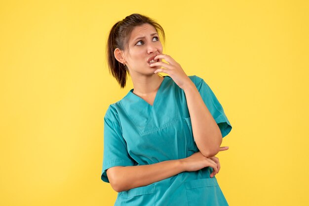 Vue de face femme médecin en chemise médicale sur fond jaune