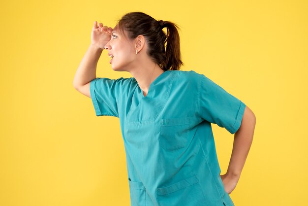 Vue de face femme médecin en chemise médicale sur fond jaune