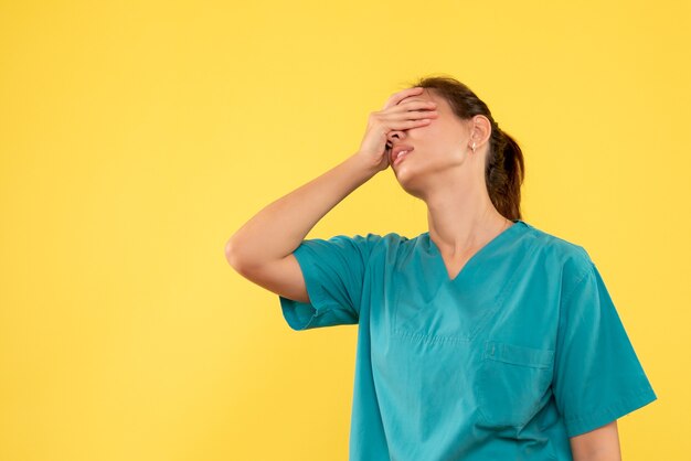 Vue de face femme médecin en chemise médicale sur fond jaune