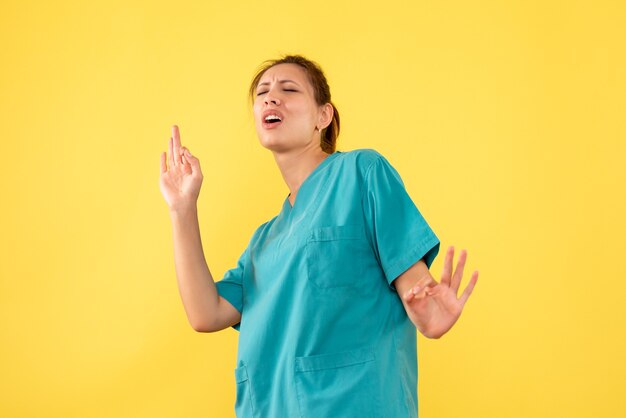 Vue de face femme médecin en chemise médicale sur fond jaune