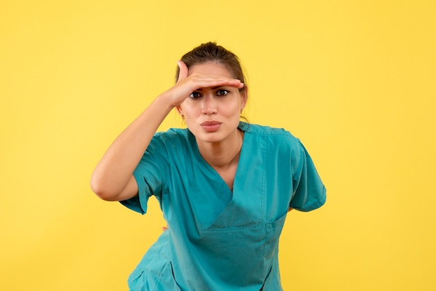 Vue de face femme médecin en chemise médicale sur fond jaune