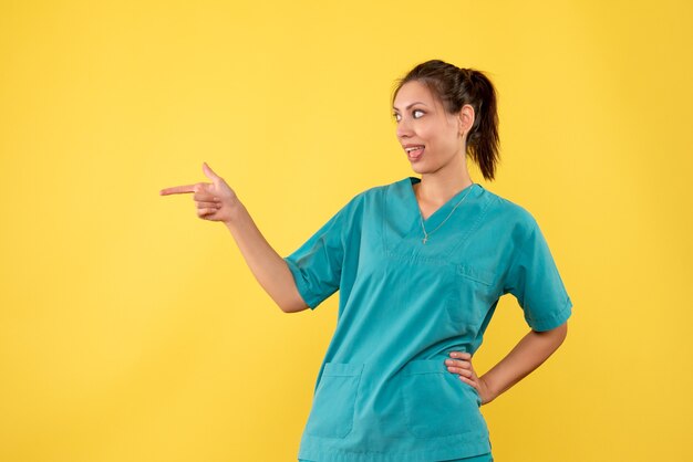 Vue de face femme médecin en chemise médicale sur fond jaune