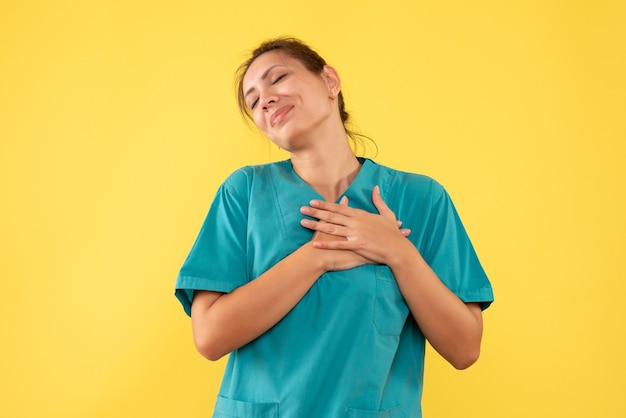 Vue de face femme médecin en chemise médicale sur fond jaune