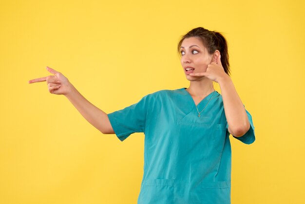 Vue de face femme médecin en chemise médicale sur fond jaune