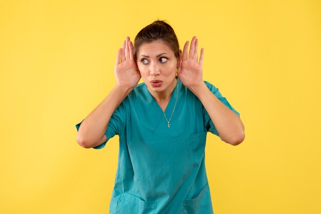 Vue de face femme médecin en chemise médicale sur fond jaune