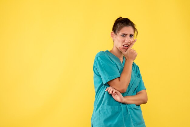 Vue de face femme médecin en chemise médicale sur fond jaune