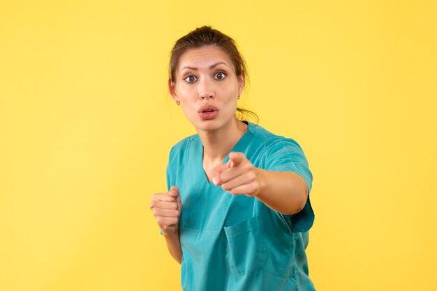 Vue de face femme médecin en chemise médicale sur fond jaune