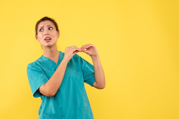 Vue de face femme médecin en chemise médicale sur fond jaune