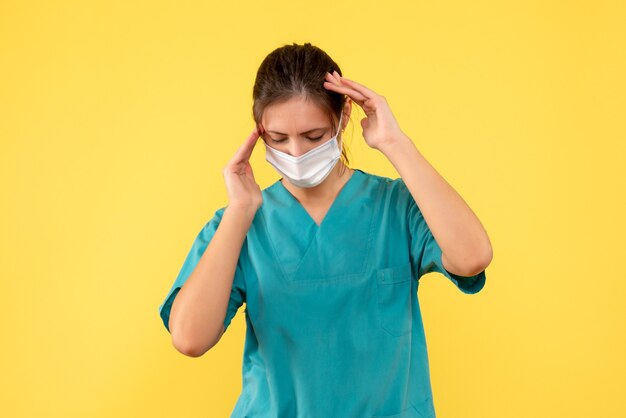 Vue de face femme médecin en chemise médicale et masque sur fond jaune