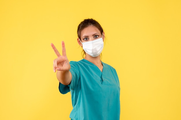 Vue de face femme médecin en chemise médicale et masque sur fond jaune