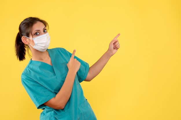 Vue de face femme médecin en chemise médicale et masque sur fond jaune