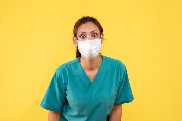 Vue de face femme médecin en chemise médicale et masque sur fond jaune