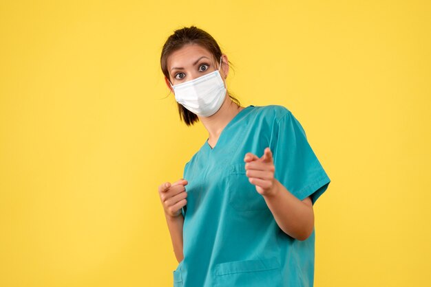 Vue de face femme médecin en chemise médicale et masque sur fond jaune