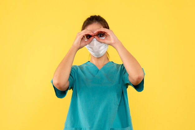 Vue de face femme médecin en chemise médicale et masque sur fond jaune