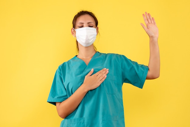 Vue De Face Femme Médecin En Chemise Médicale Et Masque Jurant Sur Fond Jaune