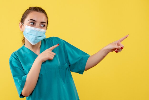 Vue de face femme médecin en chemise médicale et masque, pandémie de covid-19 de couleur de santé de virus uniforme