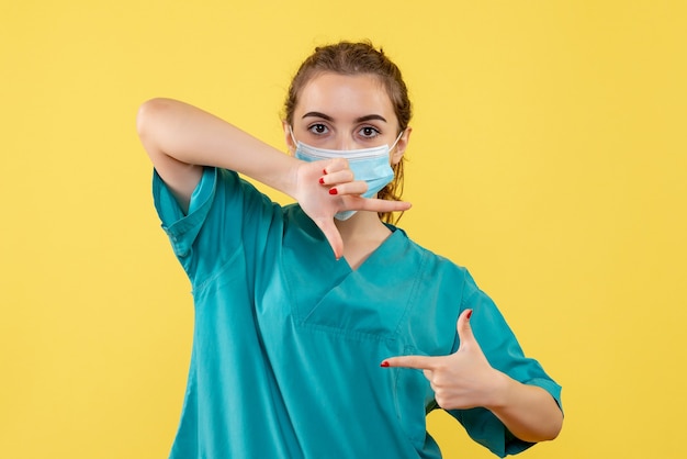 Vue de face femme médecin en chemise médicale et masque, pandémie de covid de couleur de santé de virus uniforme