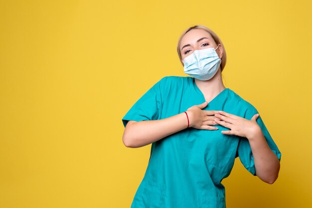 Vue de face femme médecin en chemise médicale et masque stérile sur bureau jaune infirmière infirmière santé pandémie de covid