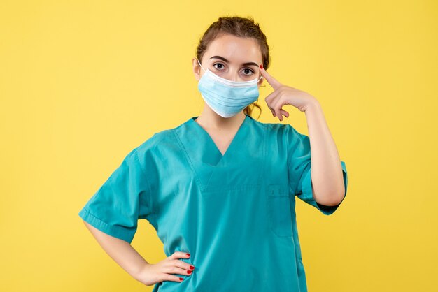 Vue de face femme médecin en chemise médicale et masque stérile, virus covid-19 couleur santé