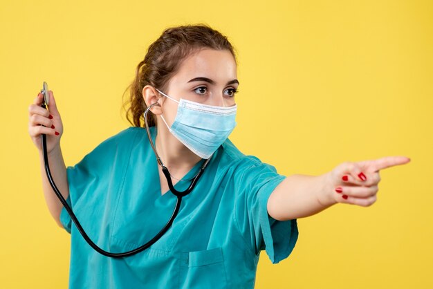 Vue de face femme médecin en chemise médicale et masque avec stéthoscope, virus couleur uniforme émotion covid santé