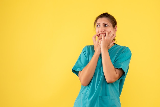 Vue de face femme médecin en chemise médicale nerveuse sur fond jaune