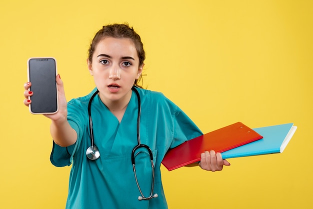 Photo gratuite vue de face femme médecin en chemise médicale avec notes et téléphone, virus de la pandémie pandémique covid-19 uniforme de l'émotion de la santé