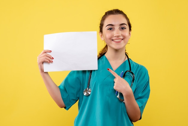 Vue de face femme médecin en chemise médicale avec papiers et stéthoscope, virus pandémique santé uniforme covid-19 émotion