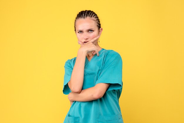 Vue de face femme médecin en chemise médicale posant et pensant, virus de la santé de couleur covid-19 infirmière
