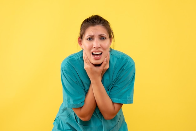 Vue de face femme médecin en chemise médicale souffrant de maux de dents sur fond jaune