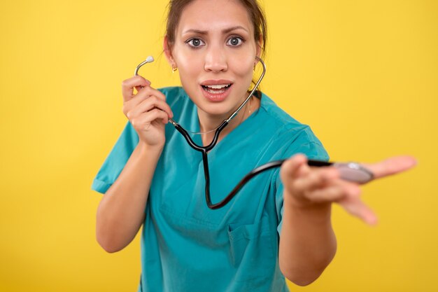 Vue de face femme médecin en chemise médicale avec stéthoscope sur fond jaune