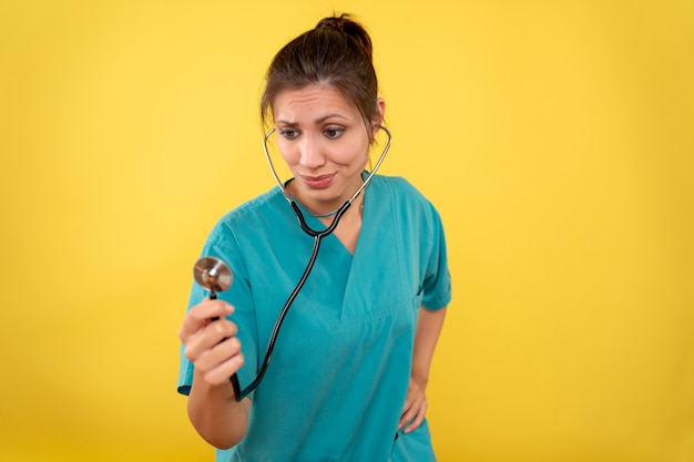 Vue de face femme médecin en chemise médicale avec stéthoscope sur fond jaune