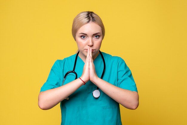 Vue de face de la femme médecin en chemise médicale avec stéthoscope sur mur jaune