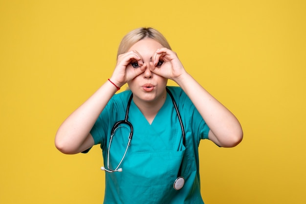 Vue de face de la femme médecin en chemise médicale avec stéthoscope sur mur jaune