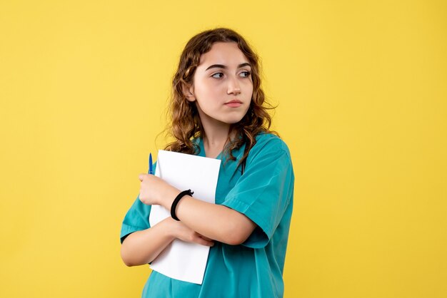 Vue de face femme médecin en chemise médicale tenant l'analyse de papier, émotion de pandémie de santé covid-19 uniforme de virus