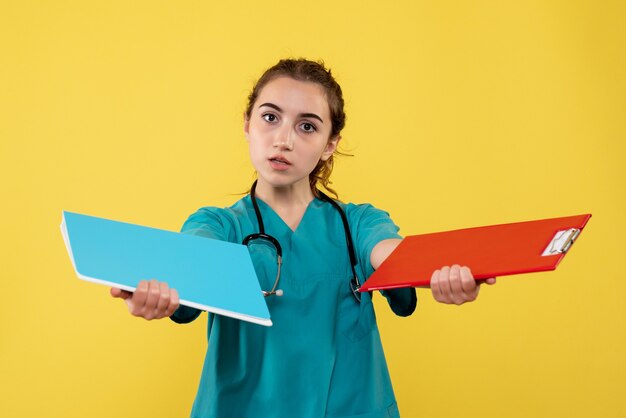 Vue de face femme médecin en chemise médicale tenant des notes, couleur virus santé émotion uniforme de la pandémie covid-19