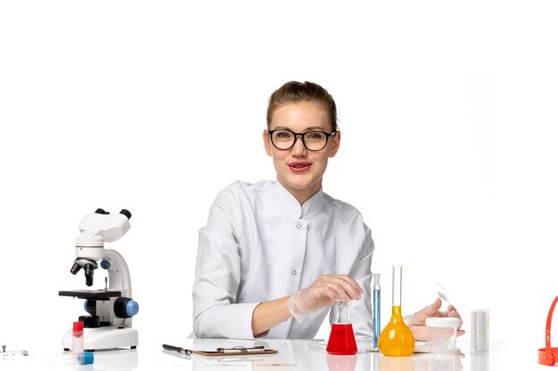 Vue de face femme médecin en combinaison médicale avec des gants en cours de travail sur l'espace blanc