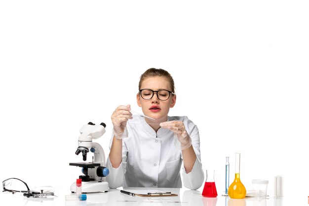 Vue de face femme médecin en combinaison médicale avec des gants travaillant avec des solutions sur l'espace blanc