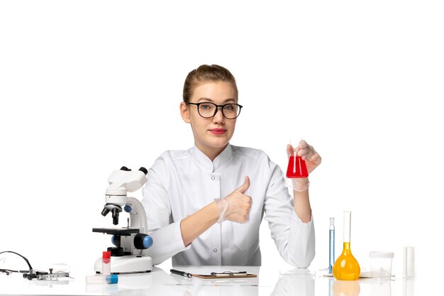 Vue de face femme médecin en combinaison médicale avec des gants travaillant avec des solutions sur l'espace blanc