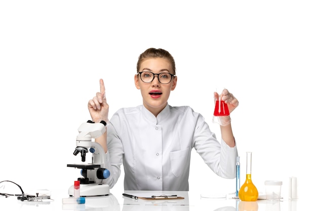 Vue de face femme médecin en combinaison médicale avec des gants travaillant avec des solutions sur l'espace blanc