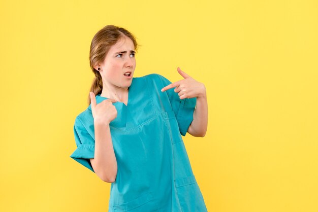 Vue de face femme médecin confuse sur fond jaune virus de couleur de l'hôpital de la santé