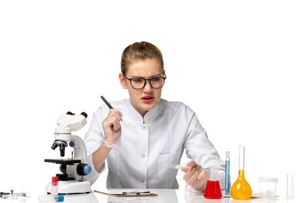 Vue de face femme médecin en costume médical blanc écrit quelque chose sur l'espace blanc