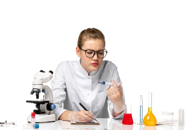 Vue de face femme médecin en costume médical blanc avec des gants tenant l'injection sur l'espace blanc-clair