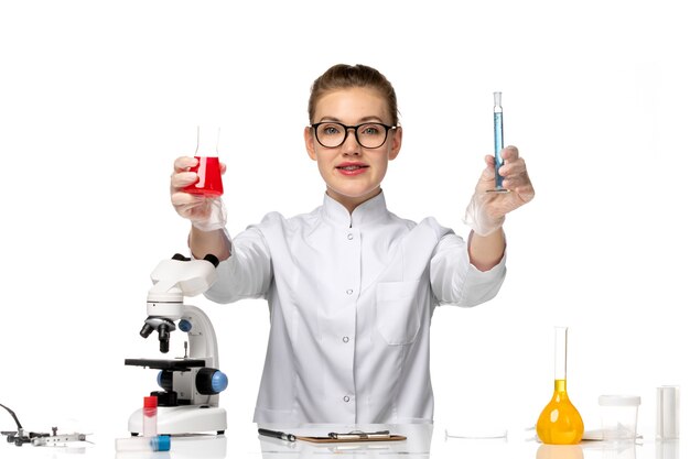 Vue de face femme médecin en costume médical blanc travaillant avec des solutions sur l'espace blanc