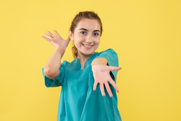 Vue de face de la femme médecin en costume médical sur le mur jaune