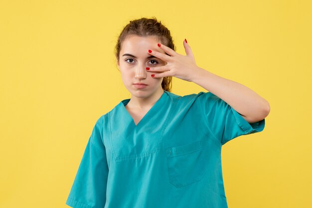 Vue de face de la femme médecin en costume médical sur le mur jaune