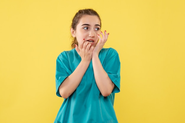 Vue de face de la femme médecin en costume médical sur le mur jaune