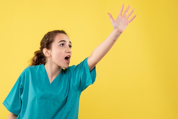 Vue de face de la femme médecin en costume médical sur le mur jaune