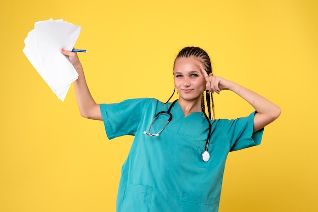 Photo gratuite vue de face de la femme médecin en costume médical avec des papiers sur mur jaune