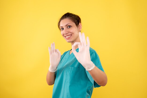 Vue de face femme médecin dans des gants sur fond jaune